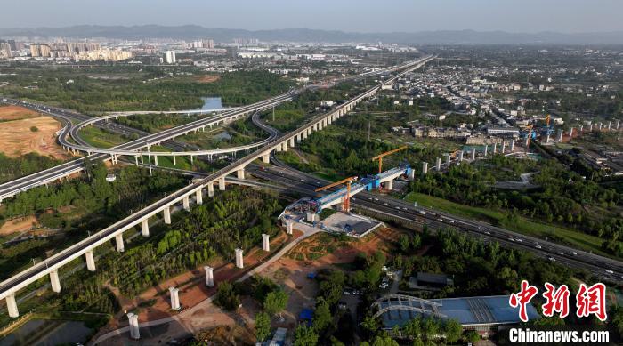 航拍正在建設(shè)的跨越成都繞城高速公路連續(xù)梁施工現(xiàn)場，旁邊依次為已運(yùn)營的成渝高速鐵路和機(jī)場高速公路?！⒅铱?攝