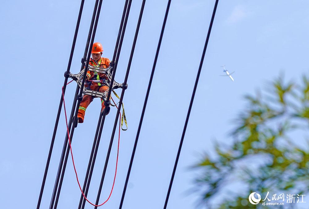 3月11日，在浙江省諸暨市河上鎮(zhèn)，浙江省送變電工程有限公司檢修人員在高空的導(dǎo)線上進(jìn)行線路檢修維護(hù)。人民網(wǎng) 章勇濤攝